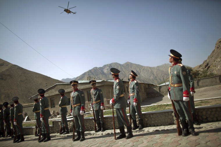 Image: Afghan honor guards watch an Afghan helicopter fly over the security handover ceremony in Panjshir province