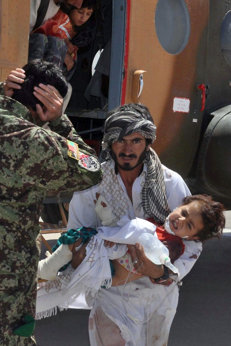 Image: An Afghan man carries an injured child from a heilicopter, after the boy was injured by a roadside bomb in Herat