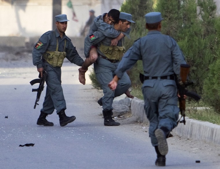 Image: A wounded Afghan policeman is carried away from the site of an attack on offices belonging to the British Council in Kabul
