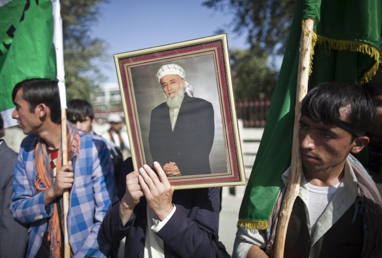 Image: A supporter of Rabbani holds his picture while standing outside his house a day after he was killed in Kabul
