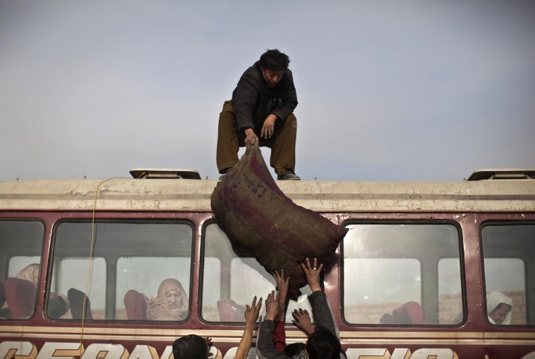 Image: Men load a sack of coal on top of a mini-bus for transportation during the distribution of winter assistance in Kabul