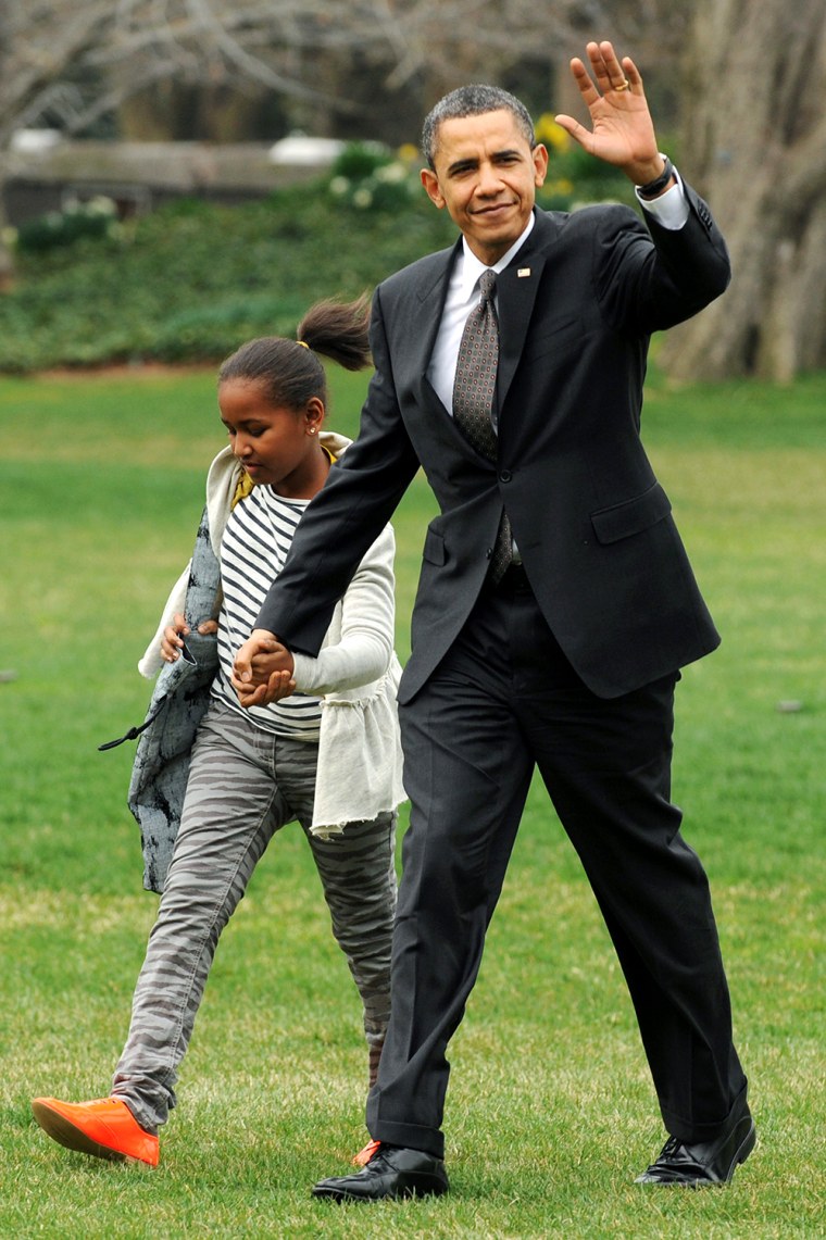 Image: US President Barack Obama waves as he arrives with his daughter Sasha (L) and the First Family on the South Lawn of the White House in Washington DC