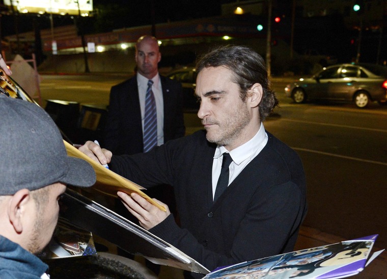 Image: Phoenix greets fans while signing an autograph as he attends the film premiere of \"Her\" at Directors Guild of America in Hollywood