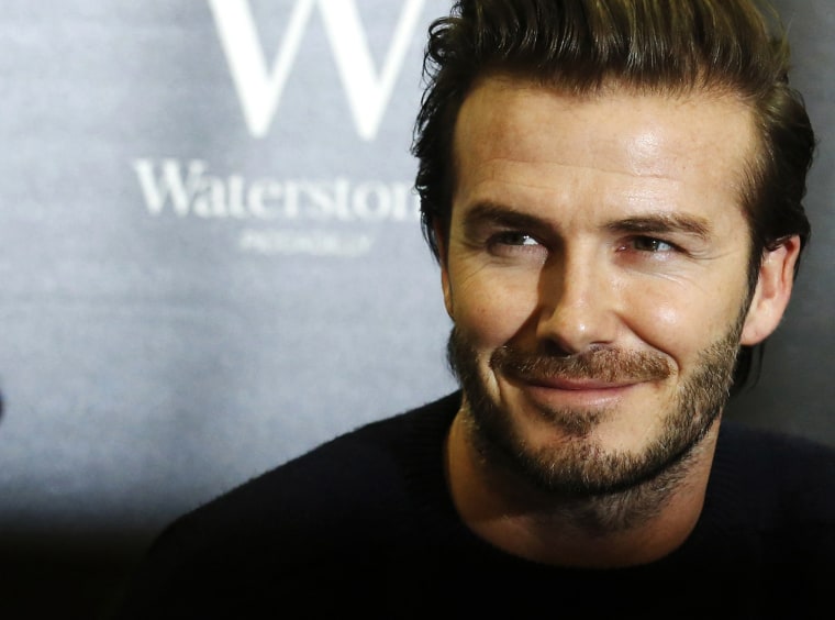 Image: Retired soccer player David Beckham poses with his book \"David Beckham\" at a bookshop in London