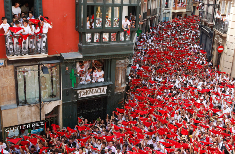 Image: Revellers hold up their red scarves during the start of the San Fermin Festival in Pamplona