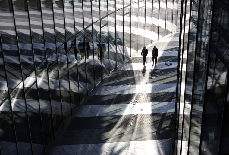 Image: Two men walk past the headquarters of the German postal and logistics group Deutsche Post AG in Bonn