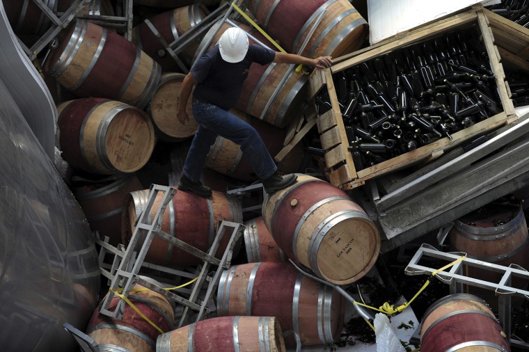 Image: Worker climbs over vats, barrels and wine bottles that were toppled and damaged by a massive earthquake in the Colchagua Valley