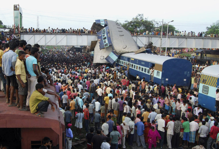 Image: Onlookers stand at the site of a train accident at Sainthia