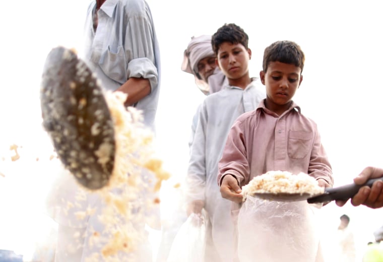 Image: A boy waits for an evening food handout at a roadside centre for flood victims near Nowshera, Pakistan
