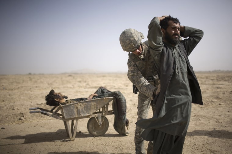 Image: A US Army soldier searches an associate of a suspected Taliban IED placer