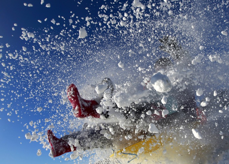 Image: A sledger's boots are visible in an explosion of snow during an attempt to jump a ramp at the Queen Elizabeth country park