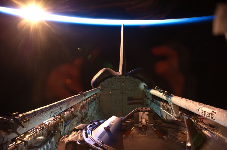 Image: An orbital sunrise brightens this view of space shuttle Discovery.