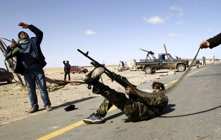 Image: A rebel fighter fires his rifle at a military aircraft loyal to Libyan leader Muammar Gaddafi at a checkpoint in Ras Lanuf