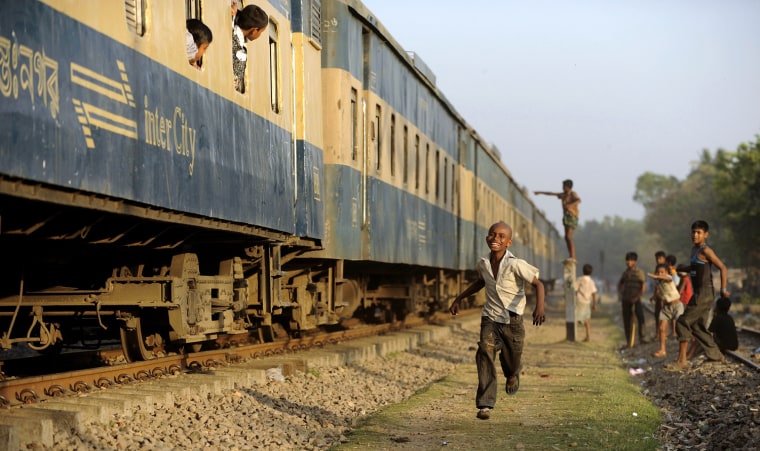 Image: A boy smiles as he runs beside a moving train in Chittagong