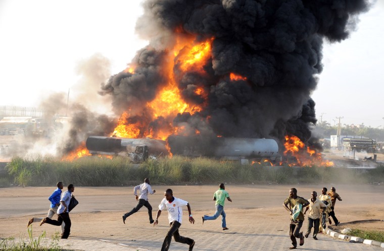 Image: Pedestrians run from the scene of a fire ravaging four fuel tankers on Lagos' Ibadan highway on May 11.
