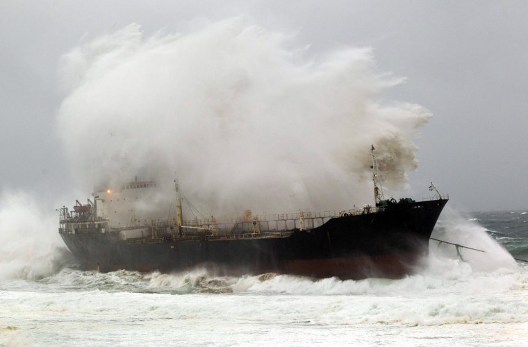 Image: A wave crashes into a ship which broke free from a tow line at Sheffield Beach