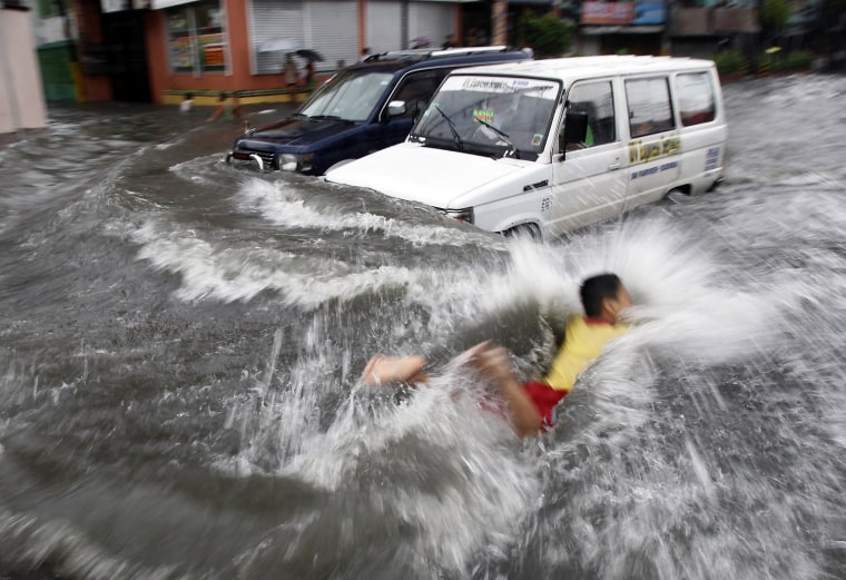 Image: A boy swims in a knee-high floodwaters brought about by continuous rainfall from Typhoon Muifa along a main street in Maceda