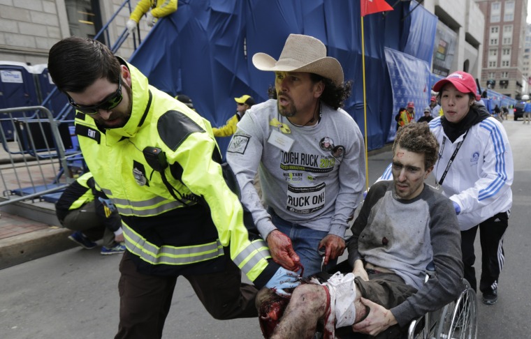 Image: Medical responders run an injured man past the finish line the 2013 Boston Marathon following an explosion in Boston