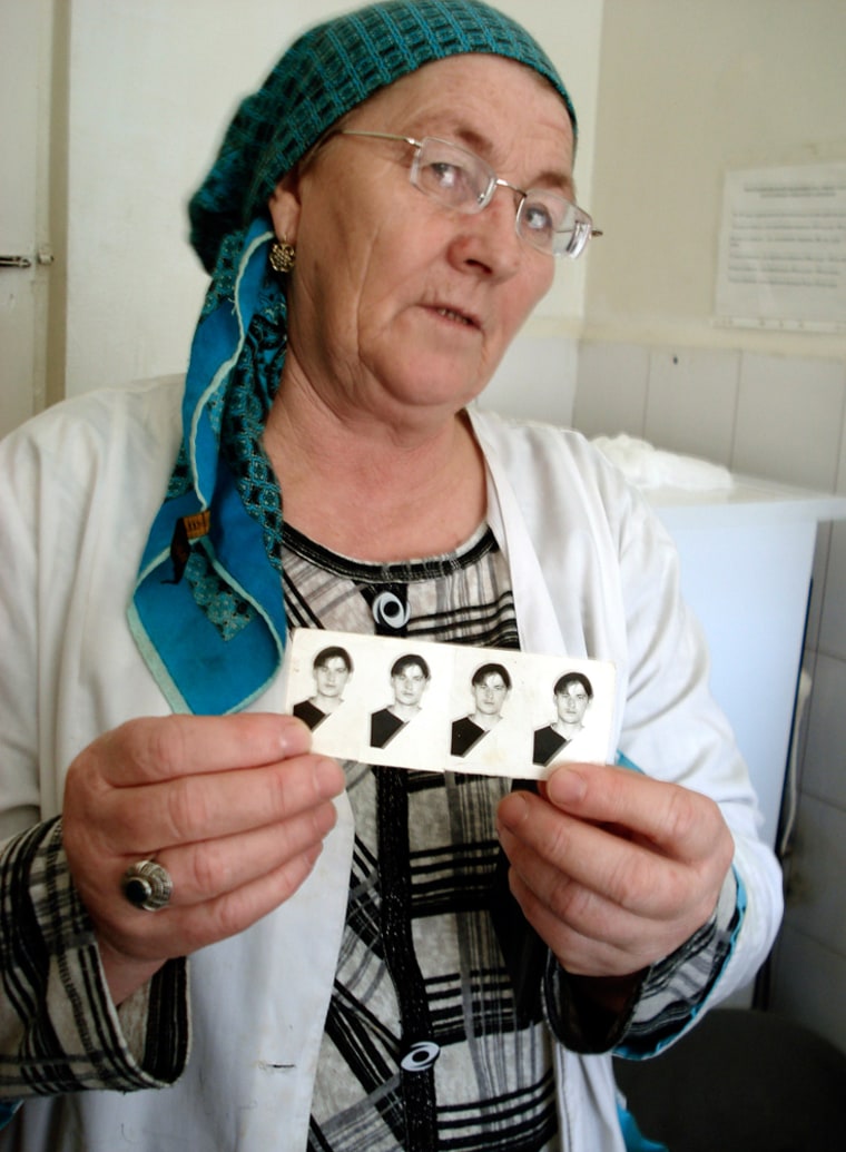 Image: Leila Pliyeva holding photos of her son Alikshan Pliyev