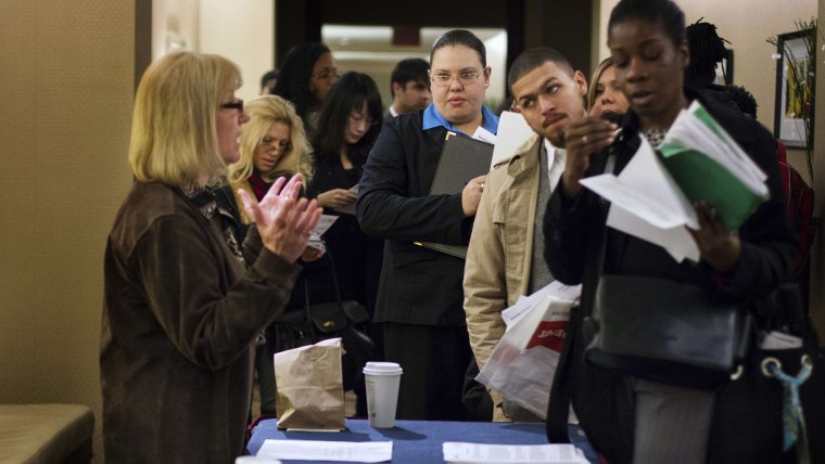 Image: Job seekers adjust their paperwork as they wait in line to attend a job fair in New York