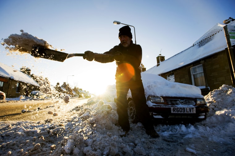 A man digs a car out from under the snow in Pathhead, Scotland, on Thursday.