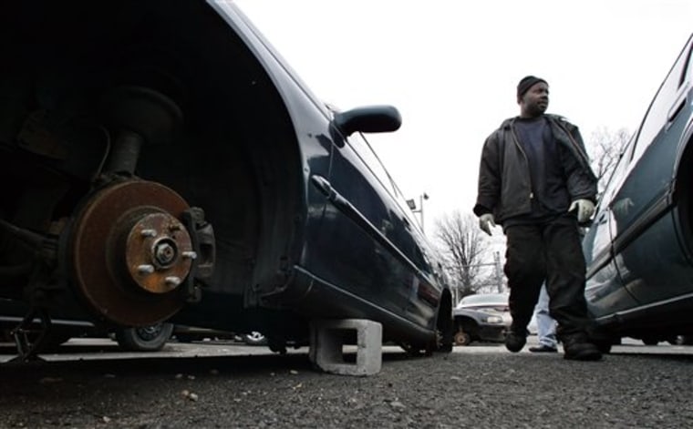Christopher Awuah walks through the lot of his JL Automotive in Newark, N.J., past cars that the wheels and tires have been stolen since the city ordered the removal of barbed wire from the top of the lot's fence. 