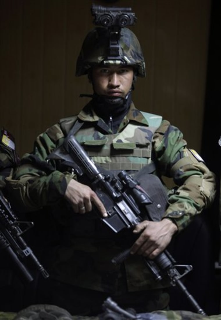 An Afghan Army commando stands in front of weapons on display for the media, in Kabul, Afghanistan on Wednesday.
