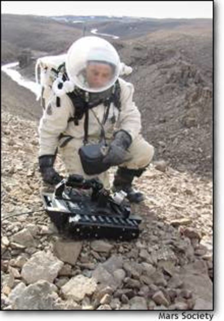 Mars Society President Robert Zubrin, who commanded two rounds of this summer's Arctic test for a Mars mission, steadies a remote-controlled telerobot atop a ridge on Devon Island during a simulated Marswalk.