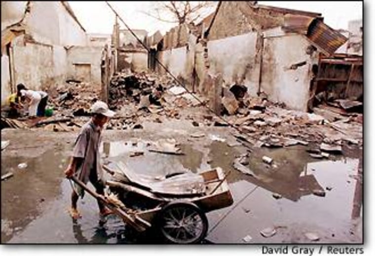An ethnic Indonesian Chinese boy pushes a cart past destroyed houses in Jakarta on May 26. The area was looted by mobs during riots which precipitated President Suharto's downfall.