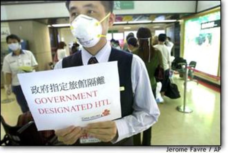 A China Airlines employee, holding a sign that reads "Government Designated Hotel," directs quarantined passengers arriving from Hong Kong at Taiwan's Chiang Kai-shek International Airport on April 28.