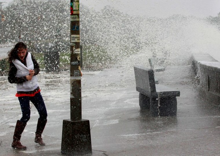 A woman reacts to waves crashing over a seawall in Narragansett, R.I., Monday, Oct. 29, 2012.  Hurricane Sandy continued on its path Monday, as the storm forced the shutdown of mass transit, schools and financial markets, sending coastal residents...