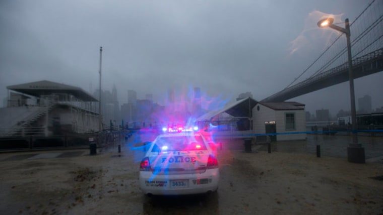 A police car patrols the Brooklyn waterfront as storm clouds blow over the Manhattan skyline in New York (Keith Bedford/Reuters)