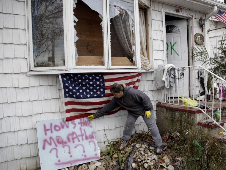 Sandra Finnegan placing a sign against the marathon on Friday in front of her brother's house, which was destroyed by Hurricane Sandy, in Staten Island, New York. (Seth Wenig/AP Photo)