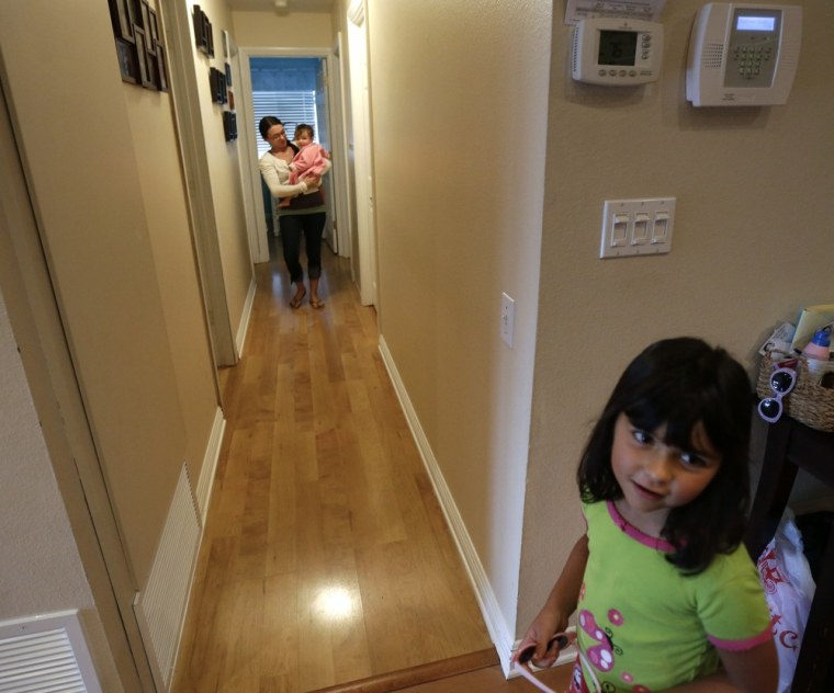 In this Sept. 26, 2012 picture, Domestic worker Alicia Wotherspoon carries Stella Widmann as she begins her day of work at the Widmann home in San Diego. Older daughter Luna Widmann looks on at right.  (AP Photo/Gregory Bull)