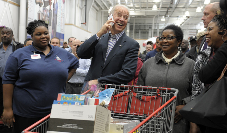 Vice President Joe Biden smiles as he makes a call on the cell phone of Costco employee Ivey Stewart, left, after shopping at the a Costco store in Washington, Thursday, Nov. 29, 2012. (AP Photo/Susan Walsh)