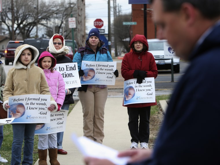 In this March 8, 2011, file photo, anti-abortion protesters gather outside the Hope Clinic for Women in Granite City, Ill., as Rev. Chris Comerford, right, from St. Elizabeth's Catholic Church in Granite City speaks out against the abortion clinic.  ...