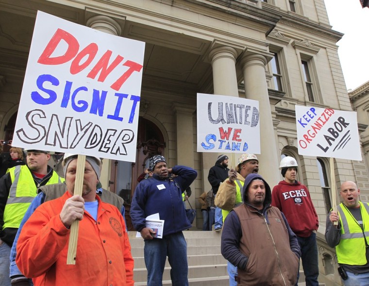 Union workers hold up a signs during a rally outside the Capitol in Lansing, Mich., as Senate Republicans introduced right-to-work legislation in the waning days of the legislative session. (Photo by Carlos Osorio/AP)