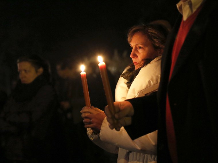 People stand with candles outside the overflow area of a vigil at the Saint Rose of Lima church in Newtown, Connecticut December 14, 2012. Twenty schoolchildren were slaughtered by a heavily armed gunman who opened fire at a suburban elementary school...