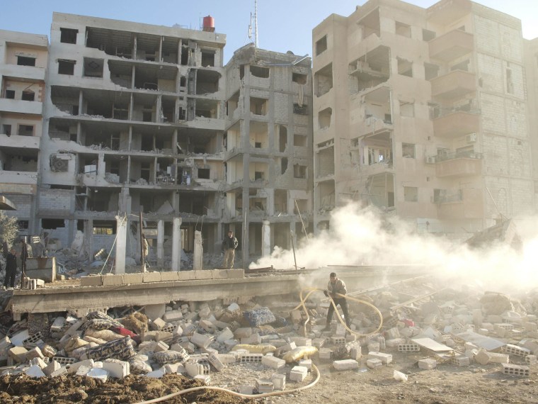 Residents stand near buildings damaged by what activists said were missiles fired by a Syrian Air Force fighter jet loyal to President Bashar al-Assad in Daraya January 17, 2013, in this picture provided by Shaam News Network . (Photo by Kenan Al...