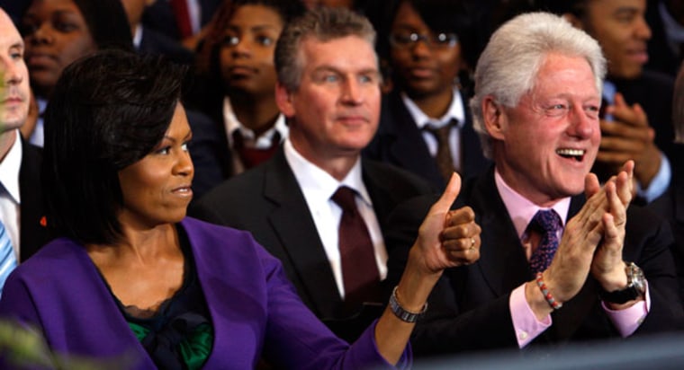 First lady MichelleObama is seated with former President BillClinton before President Barack Obama signs the Edward M. Kennedy Serve America Act at the SEED School of Washington, a public boarding school that serves inner-city students facing problems...