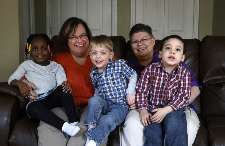 April DeBoer, second from left, sits with her adopted daughter Ryanne, 3, left, and Jayne Rowse, fourth from left, and her adopted sons  Jacob, 3, middle, and Nolan, 4, right, at their home in Hazel Park, Tuesday, March 5, 2013. (AP Photo/Paul Sancya)