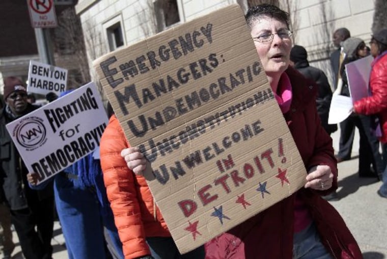 A group of protesters carry signs against an emergency financial manager being appointed to the city of Detroit as they protest outside a private club where Michigan Governor Rick Snyder was scheduled to speak in downtown Detroit, Michigan March 8,...