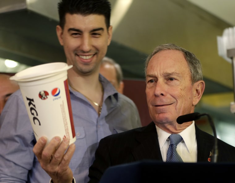 New York City Mayor Michael Bloomberg looks at a 64oz cup, as  Lucky's Cafe owner Greg Anagnostopoulos, left, stands behind him, during a news conference at the cafe in New York, Tuesday, March 12, 2013.  (AP Photo/Seth Wenig)