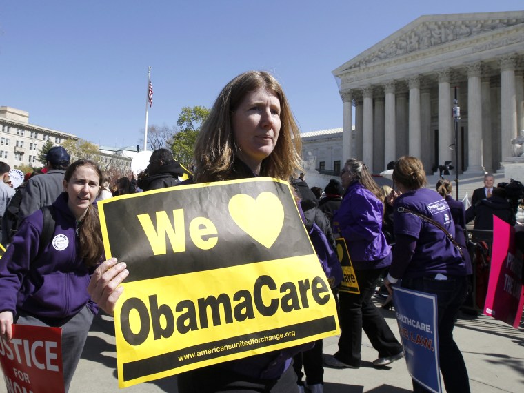 File Photo: Holding a sign saying \"We Love ObamaCare\" supporters of health care reform rally in front of the Supreme Court in Washington, Tuesday, March 27, 2012, as the court continued hearing arguments on the health care law signed by President...