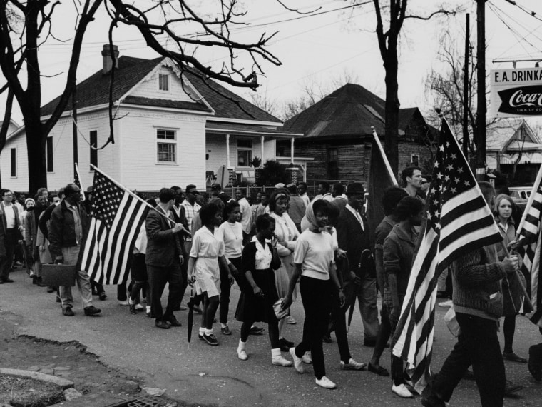 Circa 1965:  Participants, some carrying American flags, marching in the civil rights march from Selma to Montgomery, Alabama in 1965  (Photo by Buyenlarge/Getty Images, File)