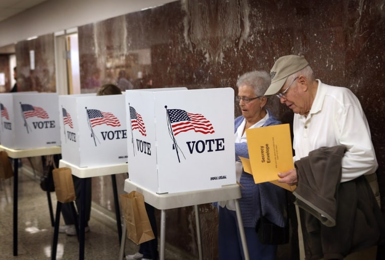 Betty Carlson (L) helps her husband Keith Carlson, who is visually impaired, fill out his ballot during early voting at the Black Hawk County Courthouse on September 27, 2012 in Waterloo, Iowa. In the 2008 election, 36% of voters cast an early ballot...