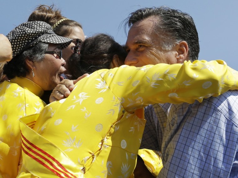 Mitt Romney embraces women wearing traditional Vietnamese \"ao dai\" dresses as he campaigns at Van Dyck Park in Fairfax, Va., Thursday, Sept. 13, 2012.