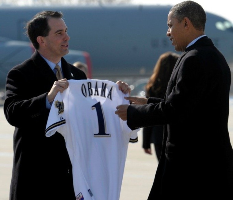 Wisconsin Gov. Scott Walker presents President Barack Obama with a Milwaukee Brewers baseball jersey upon his arrival at General Mitchell International Airport in Milwaukee, Wednesday, Feb. 15, 2012.