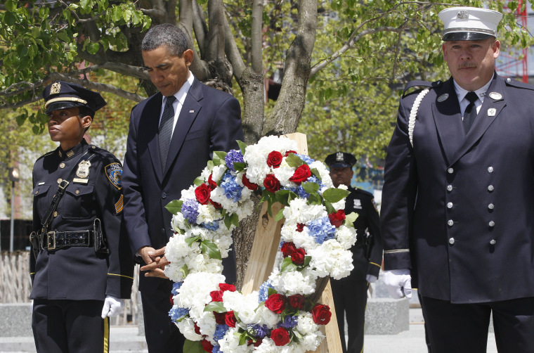 President Obama, accompanied by a New York City Police officer, New York City Firefighter, and Port Authority officer, observes a moment of silence after placing a wreath beside the \"Survivor Tree\" (left) at the World Trade Center site.