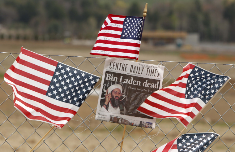 A newspaper front page and flags are attached to the fence overlooking the crash site at the temporary memorial to United Flight 93 in Shanksville, PA.
